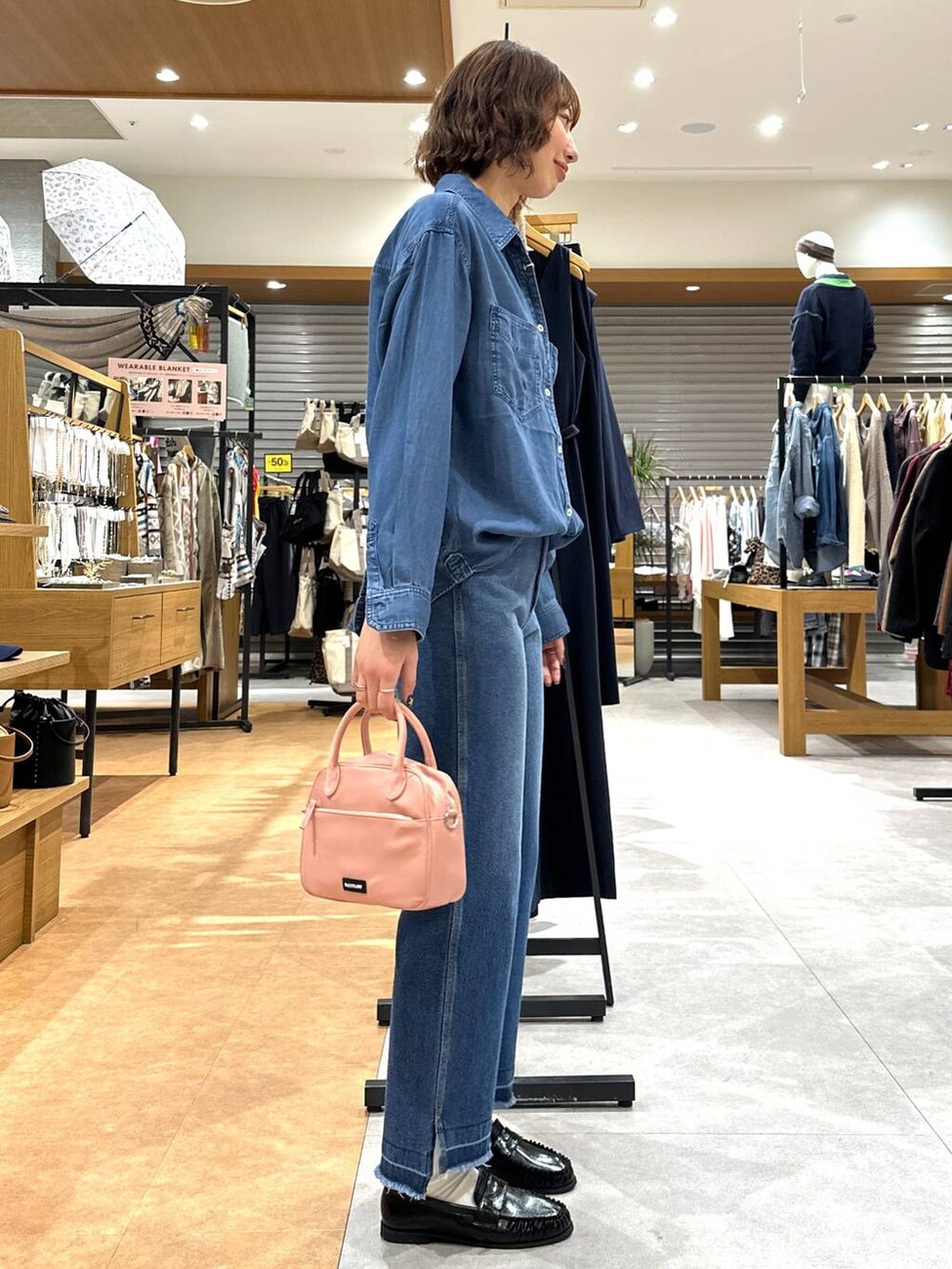 ブルー系のデニムパンツ、ブルー系のシャツ/ブラウス、ピンク系のハンドバッグを着用したレディースの冬コーディネートの3枚目の写真