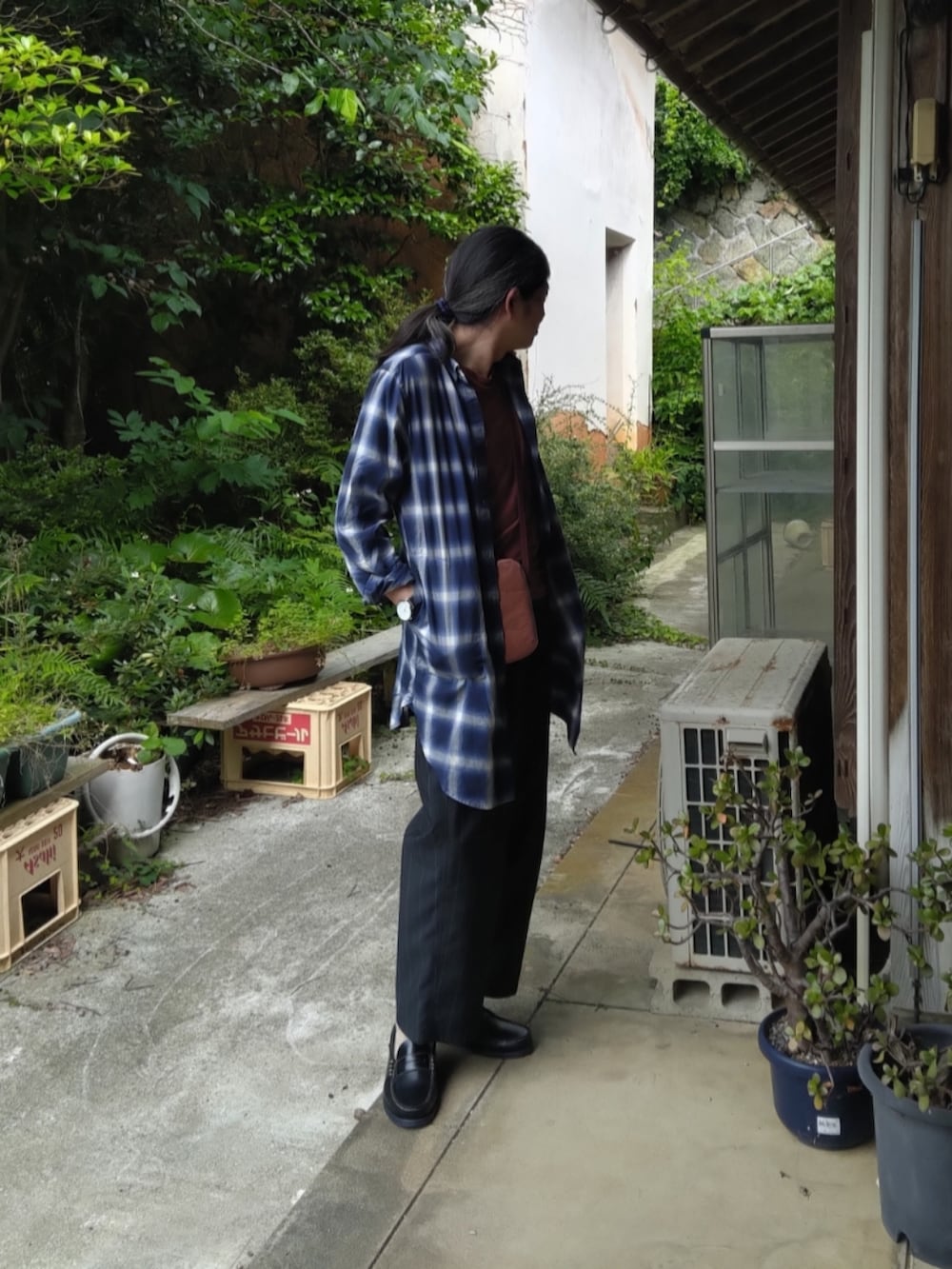 ブラック系のスラックス、ブルー系のローファー、オレンジ系のTシャツ/カットソーを着用したメンズの夏コーディネートの2枚目の写真
