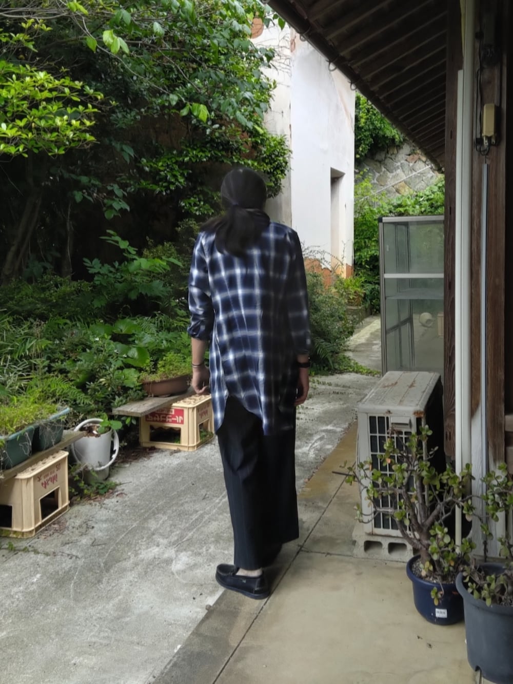 ブラック系のスラックス、ブルー系のローファー、オレンジ系のTシャツ/カットソーを着用したメンズの夏コーディネートの3枚目の写真