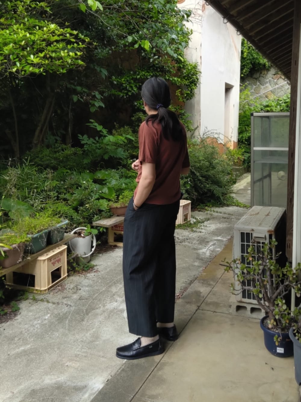 ブラック系のスラックス、ブルー系のローファー、オレンジ系のTシャツ/カットソーを着用したメンズの夏コーディネートの5枚目の写真