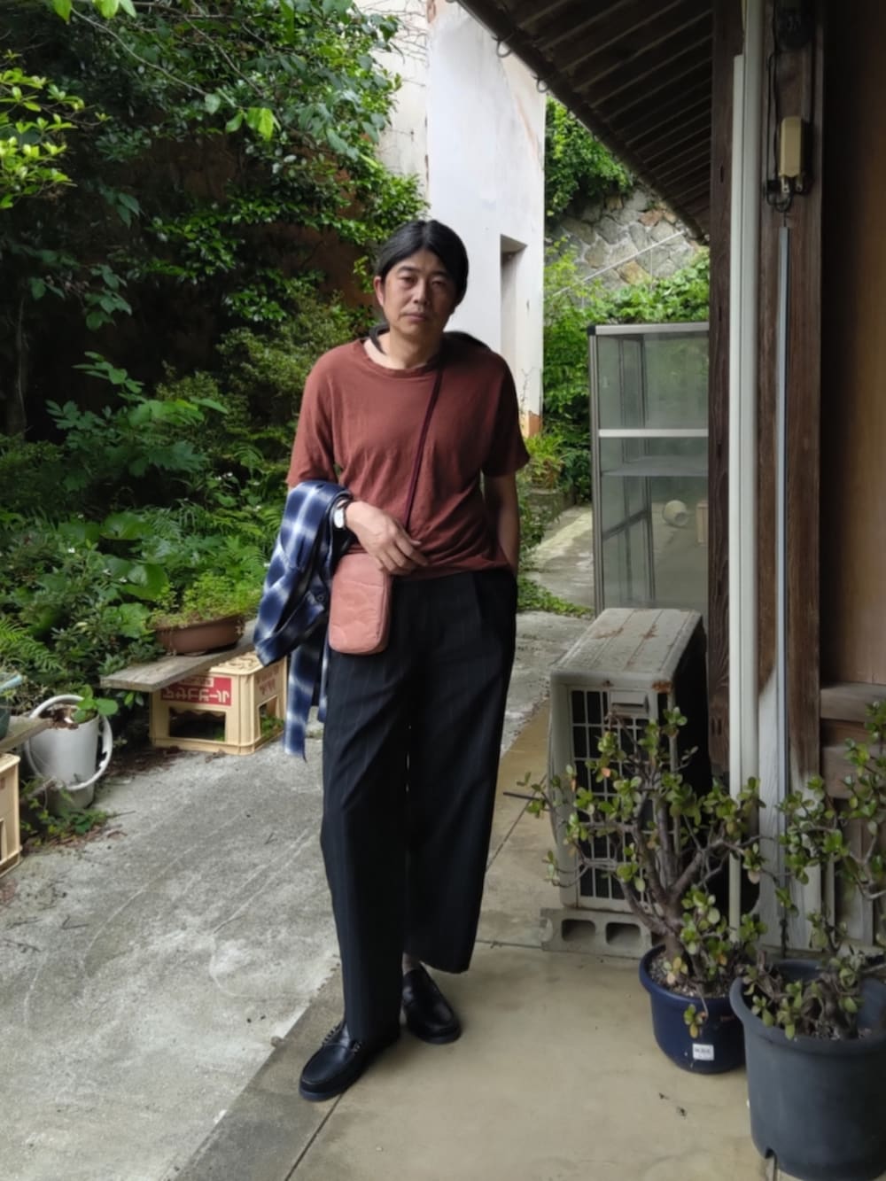 ブラック系のスラックス、ブルー系のローファー、オレンジ系のTシャツ/カットソーを着用したメンズの夏コーディネートの4枚目の写真