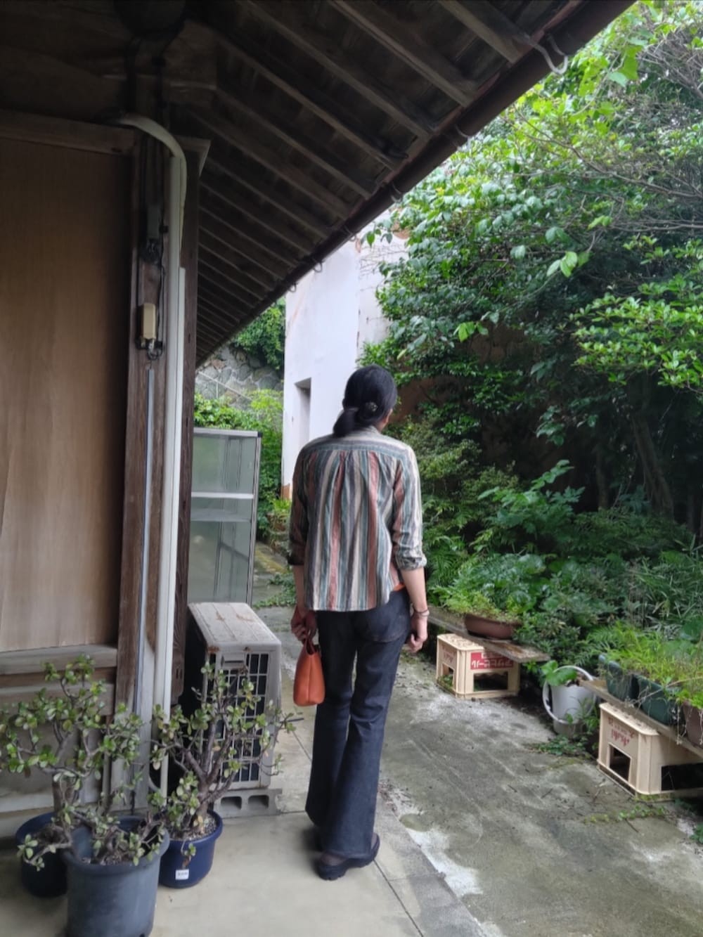 オレンジ系のTシャツ/カットソー、ブルー系のデニムパンツ、ブラウン系のスニーカーを着用したメンズの夏コーディネートの3枚目の写真
