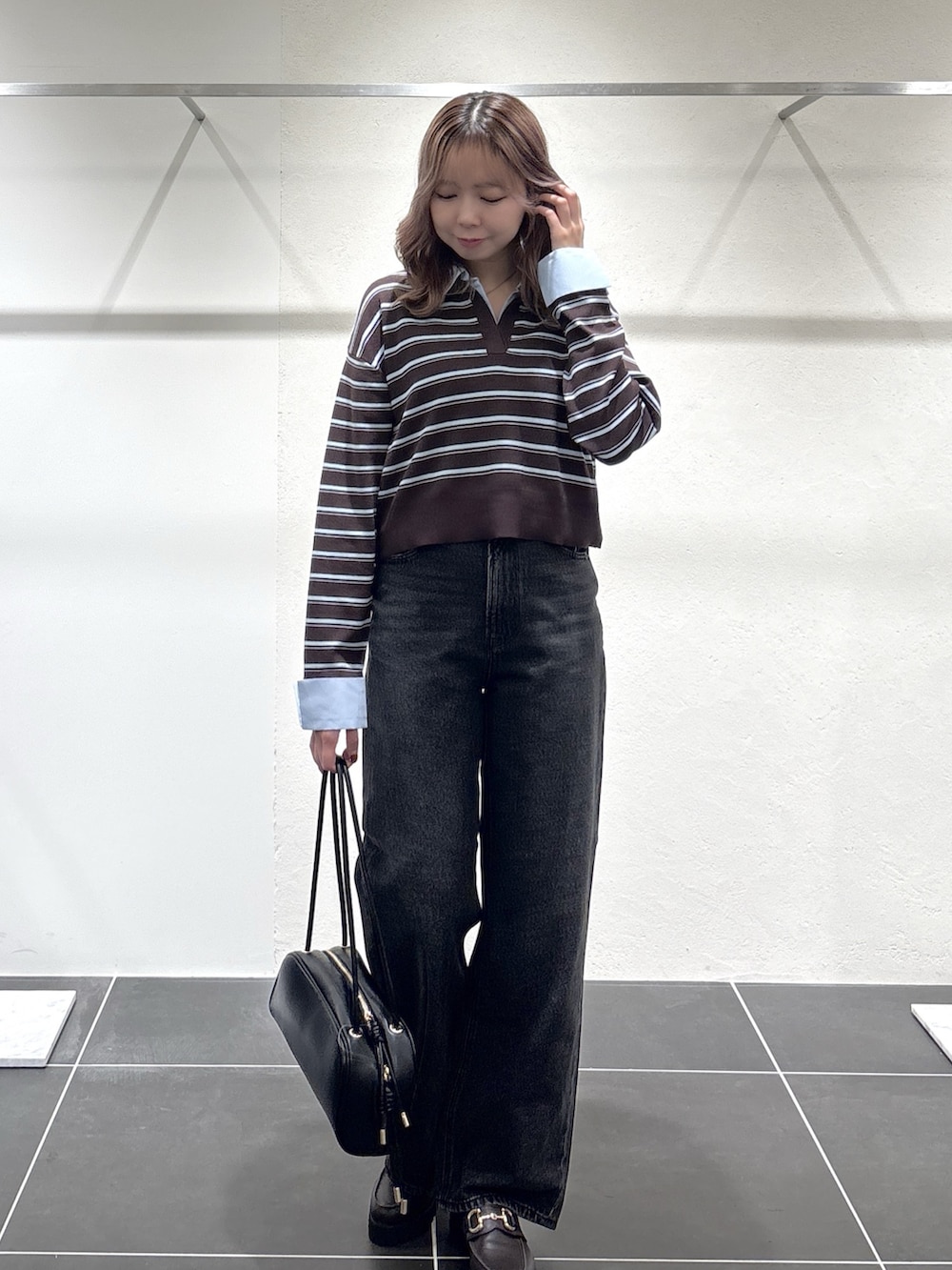 ブラック系のデニムパンツ、ブラック系のボストンバッグ、ブラウン系のローファーを着用したレディースの秋コーディネートの5枚目の写真