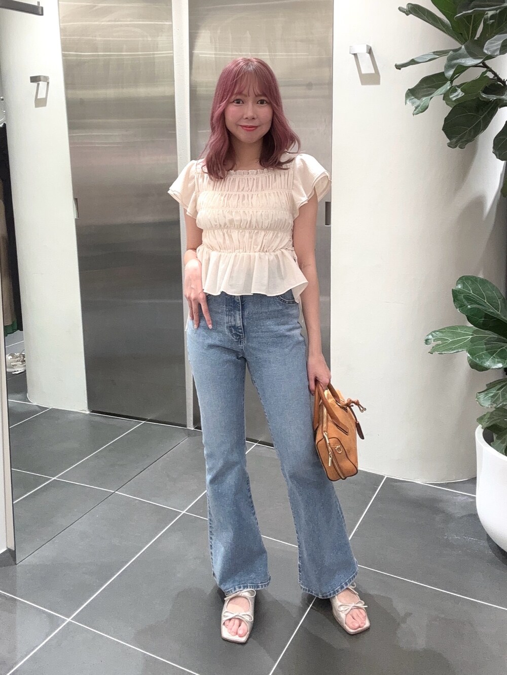 ブルー系のデニムパンツ、オレンジ系のボストンバッグ、ホワイト系のシャツ/ブラウスを着用したレディースの夏コーディネートの4枚目の写真