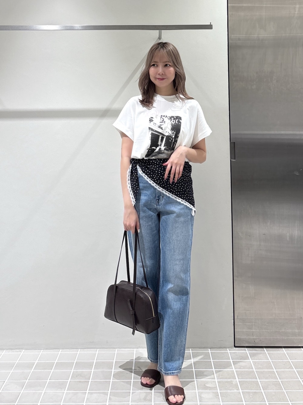 ホワイト系のTシャツ/カットソー、ブルー系のデニムパンツ、ブラウン系のボストンバッグを着用したレディースの夏コーディネートの2枚目の写真