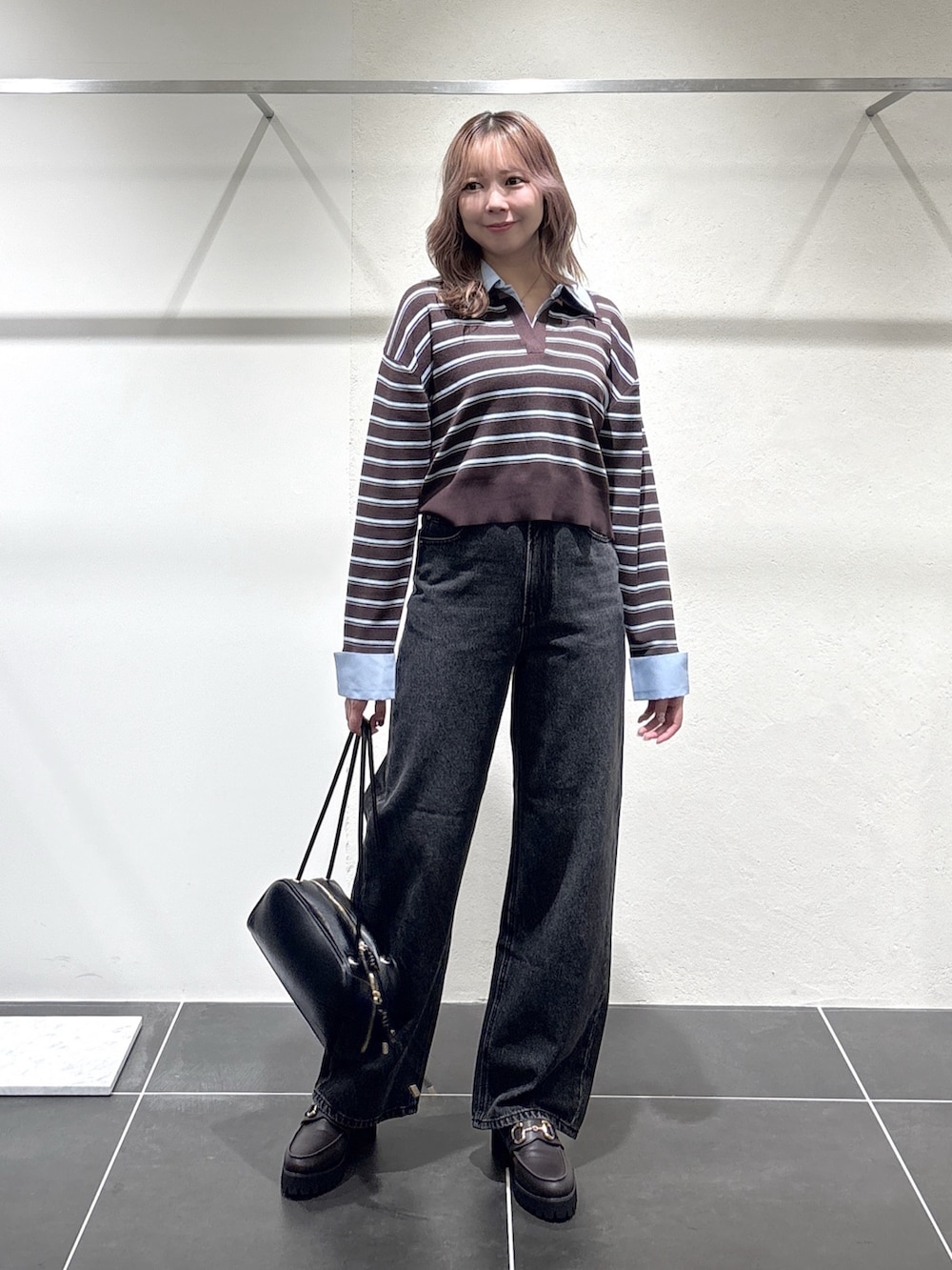 ブラック系のデニムパンツ、ブラック系のボストンバッグ、ブラウン系のローファーを着用したレディースの秋コーディネートの2枚目の写真