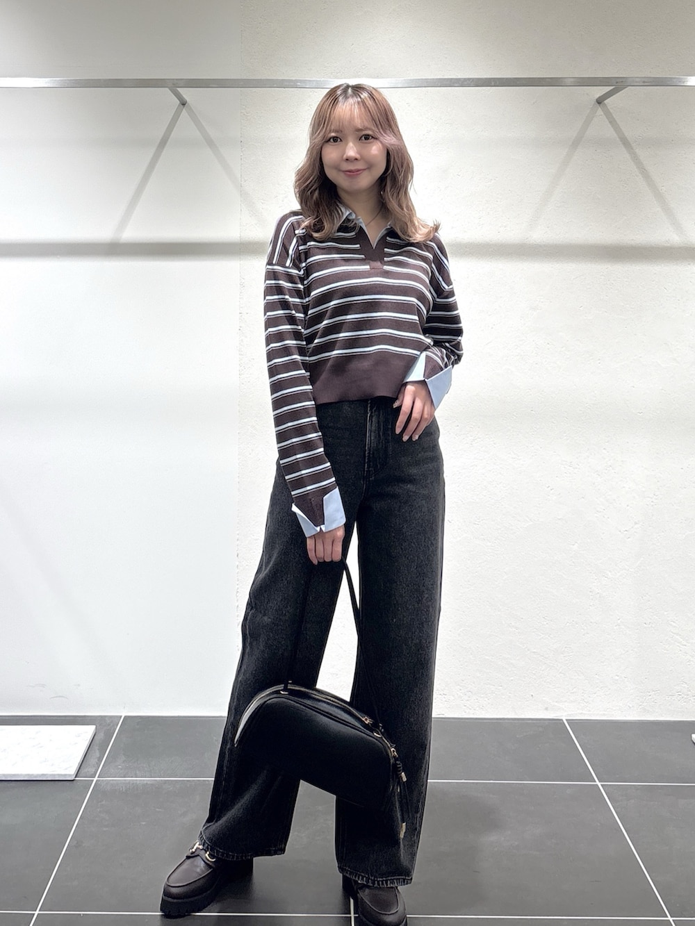 ブラック系のデニムパンツ、ブラック系のボストンバッグ、ブラウン系のローファーを着用したレディースの秋コーディネートの4枚目の写真