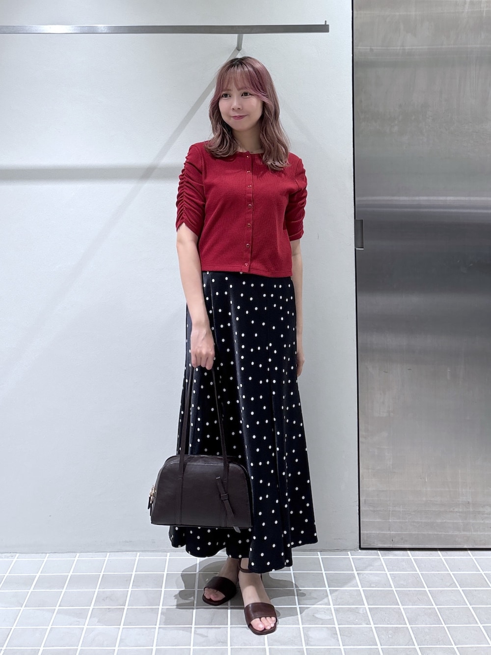 レッド系のTシャツ/カットソー、ブラック系のスカート、ブラウン系のボストンバッグを着用したレディースの夏コーディネートの2枚目の写真