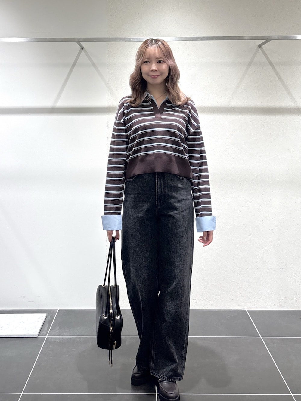 ブラック系のデニムパンツ、ブラック系のボストンバッグ、ブラウン系のローファーを着用したレディースの秋コーディネートの3枚目の写真
