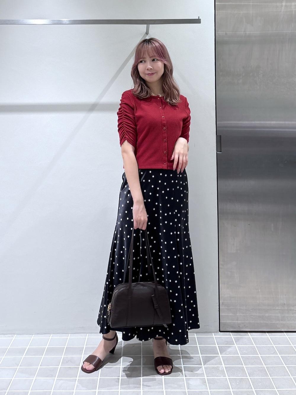 レッド系のTシャツ/カットソー、ブラック系のスカート、ブラウン系のボストンバッグを着用したレディースの夏コーディネートの3枚目の写真