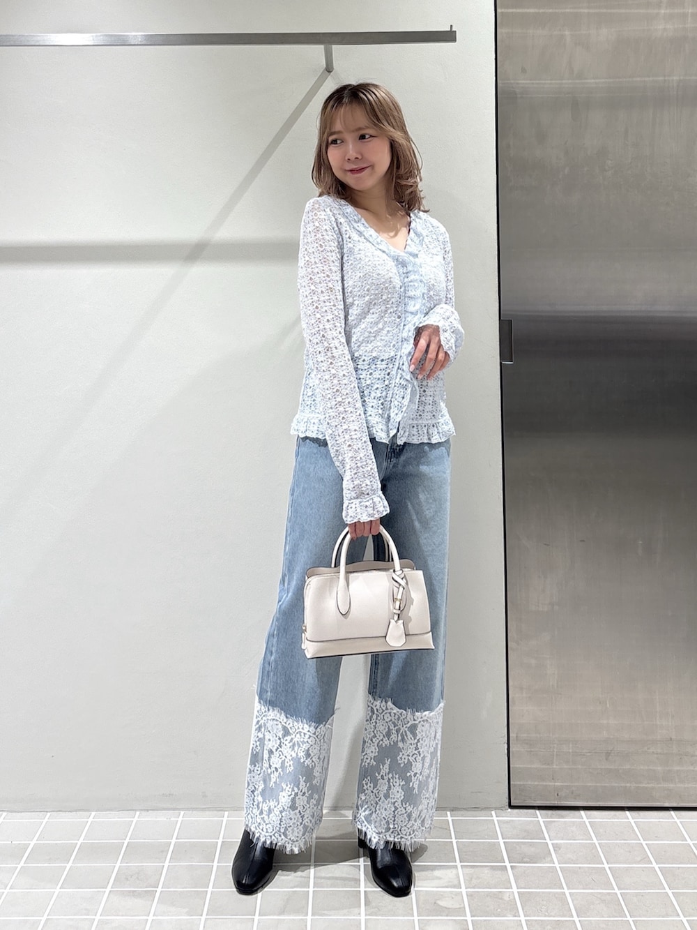 ホワイト系のカーディガン/ボレロ、ブルー系のデニムパンツ、ブラック系のブーツを着用したレディースの夏コーディネートの2枚目の写真