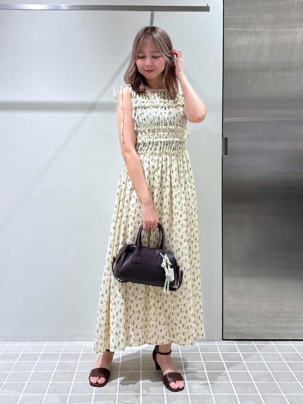 ホワイト系のワンピース、ブラウン系のボストンバッグ、ブラウン系のサンダルを着用したレディースの夏コーディネートの2枚目の写真