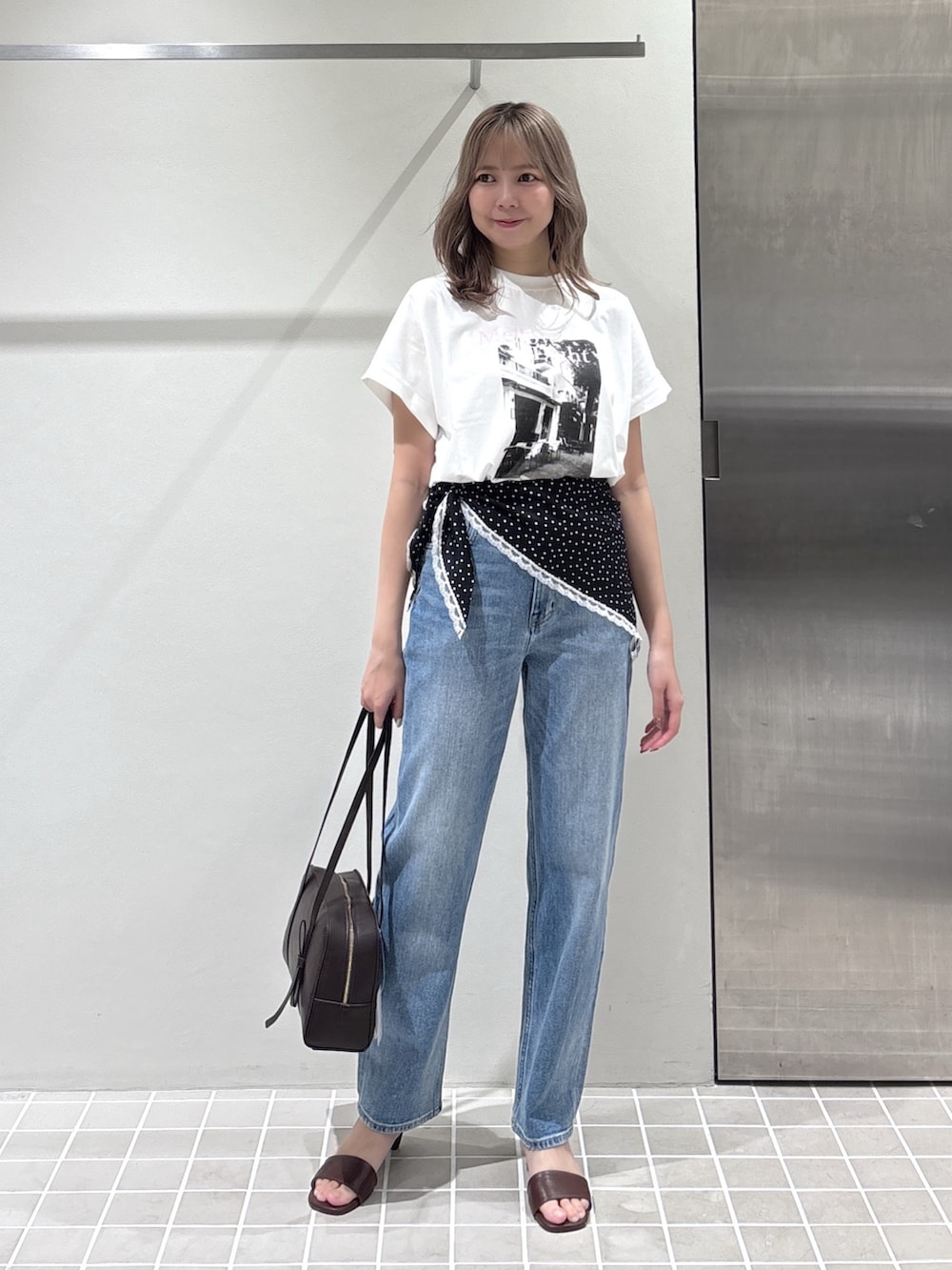 ホワイト系のTシャツ/カットソー、ブルー系のデニムパンツ、ブラウン系のボストンバッグを着用したレディースの夏コーディネートの3枚目の写真