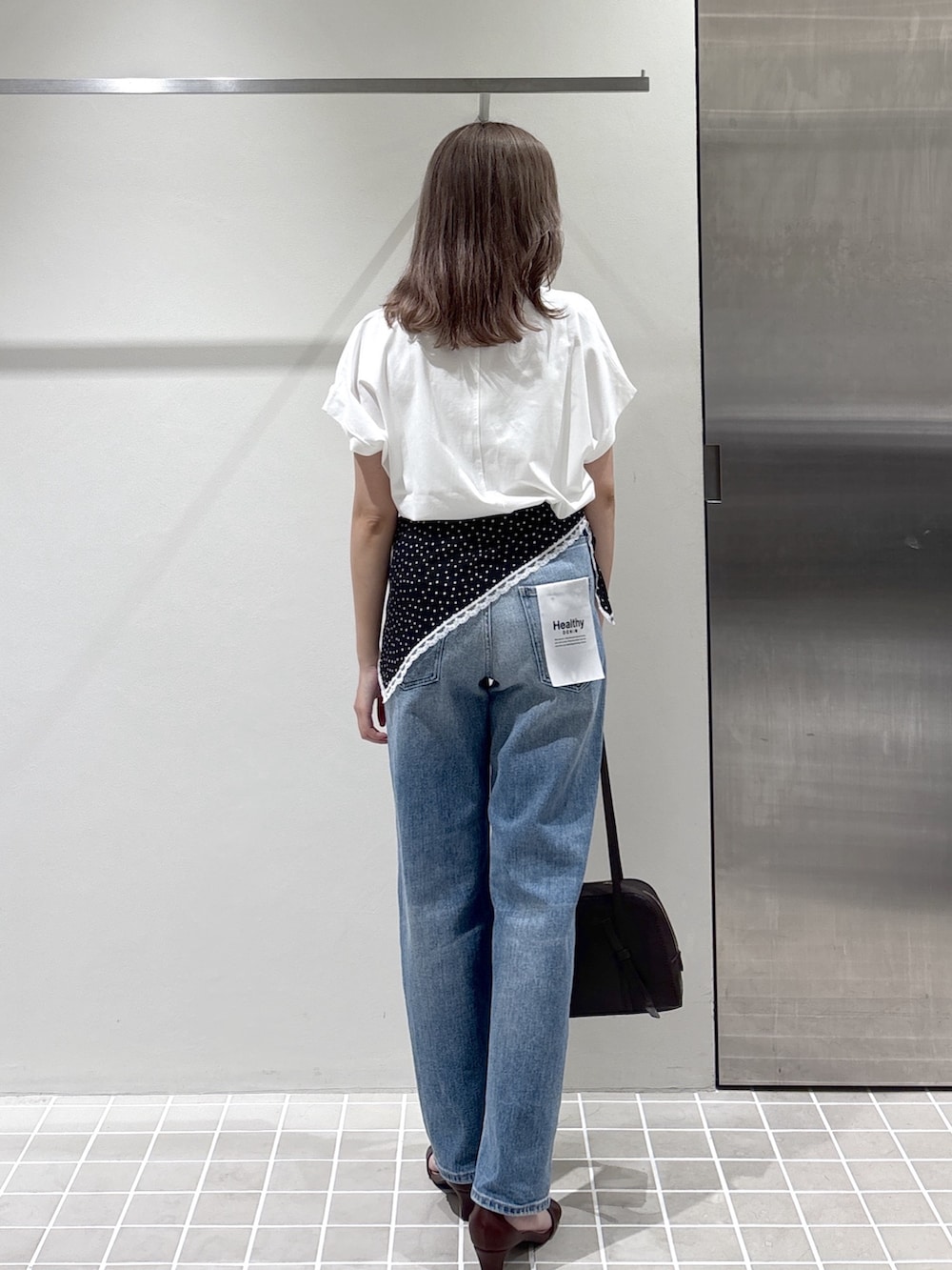 ホワイト系のTシャツ/カットソー、ブルー系のデニムパンツ、ブラウン系のボストンバッグを着用したレディースの夏コーディネートの6枚目の写真