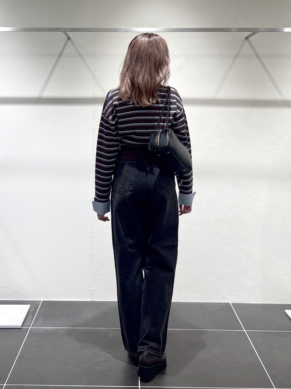 ブラック系のデニムパンツ、ブラック系のボストンバッグ、ブラウン系のローファーを着用したレディースの秋コーディネートの6枚目の写真