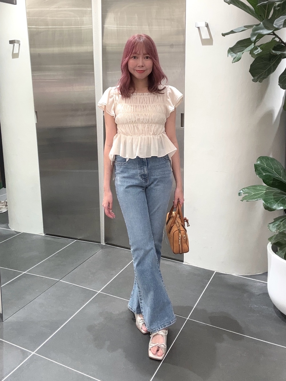 ブルー系のデニムパンツ、オレンジ系のボストンバッグ、ホワイト系のシャツ/ブラウスを着用したレディースの夏コーディネートの2枚目の写真