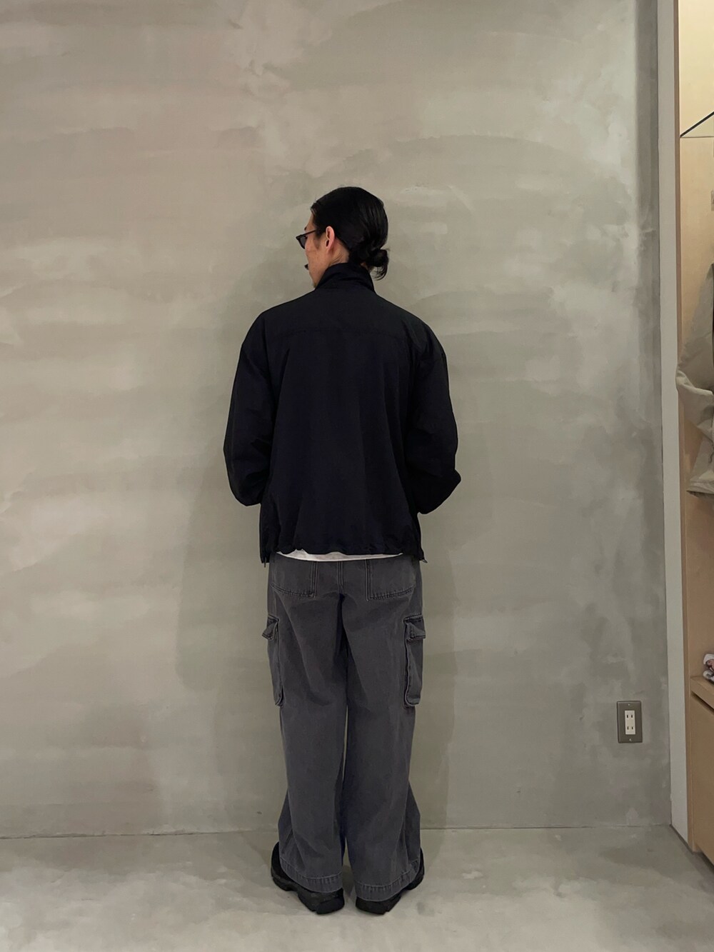 ブラック系のナイロンジャケット、ブラック系のカーゴパンツ、ブラック系のスニーカーを着用したメンズの春コーディネートの2枚目の写真