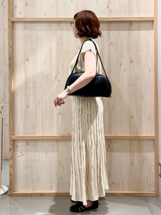 ホワイト系のニット/セーター、ベージュ系のスカート、ブラック系のトートバッグを着用したレディースの夏コーディネートの4枚目の写真
