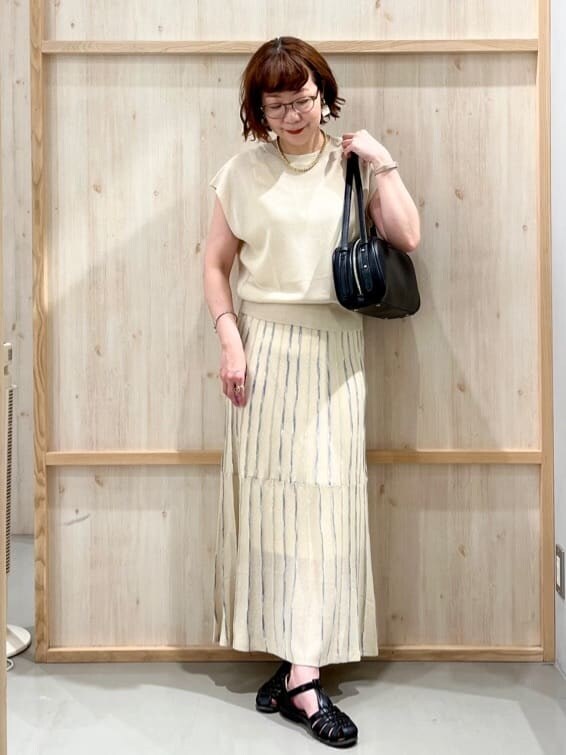 ホワイト系のニット/セーター、ベージュ系のスカート、ブラック系のトートバッグを着用したレディースの夏コーディネートの3枚目の写真