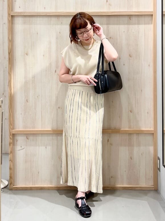 ホワイト系のニット/セーター、ベージュ系のスカート、ブラック系のトートバッグを着用したレディースの夏コーディネートの2枚目の写真