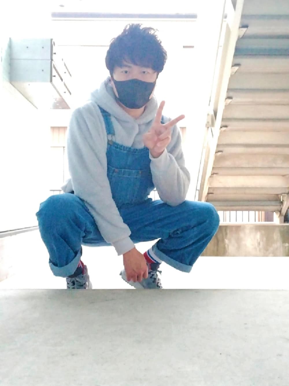 グレー系のパーカー、ブルー系のサロペット/オーバーオール、グレー系のスニーカーを着用したメンズの春コーディネートの2枚目の写真