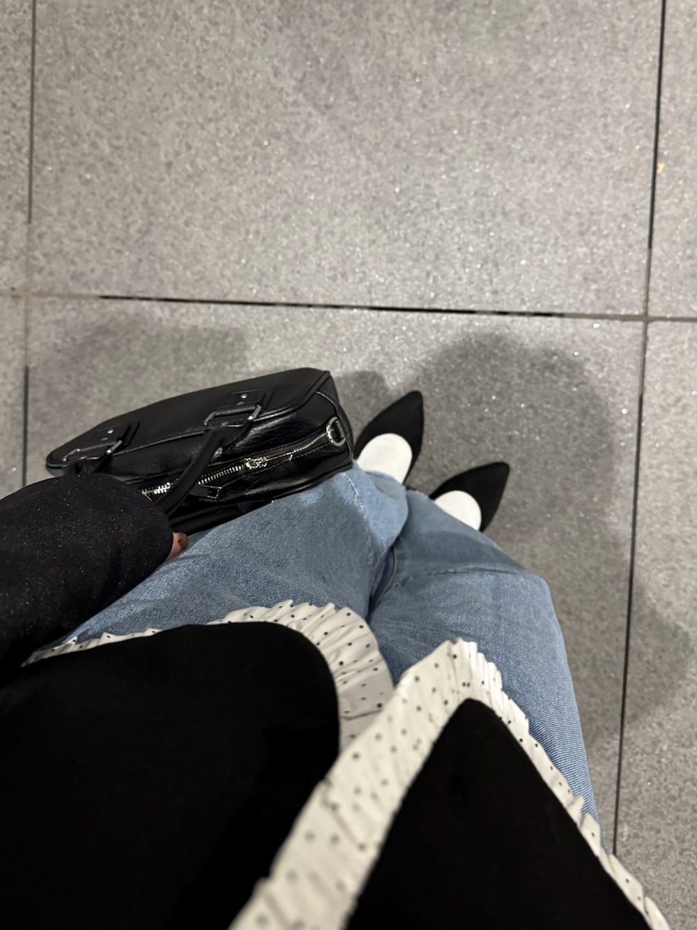 ブルー系のデニムパンツ、ブラック系のショルダーバッグ、ブラック系のテーラードジャケットを着用したレディースの冬コーディネートの2枚目の写真