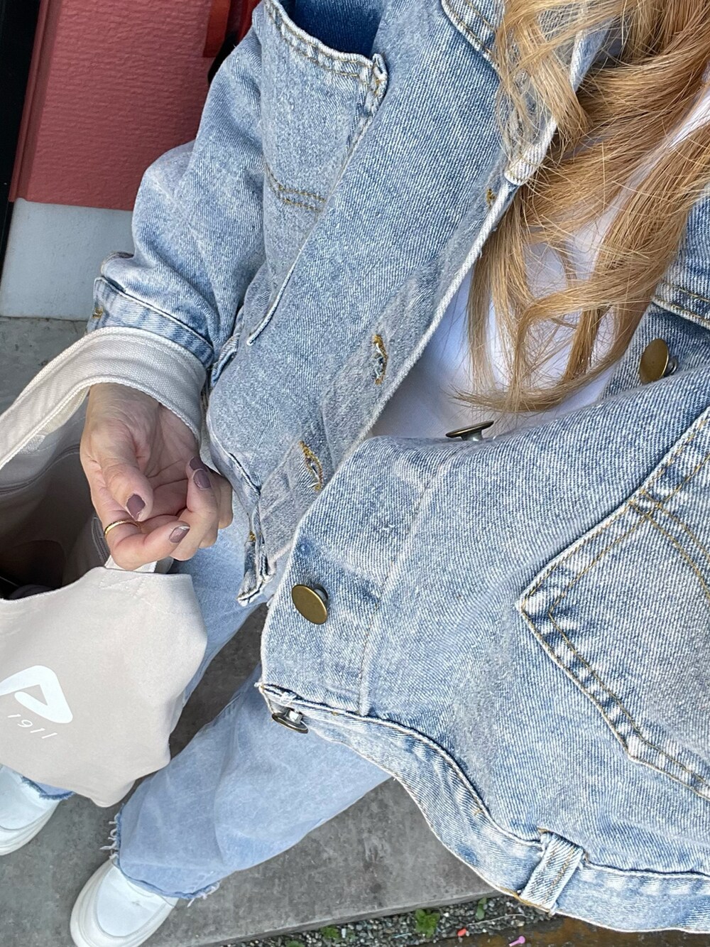 ベージュ系のトートバッグ、ブルー系のデニムパンツ、ブルー系のデニムジャケットを着用したレディースの春コーディネートの2枚目の写真