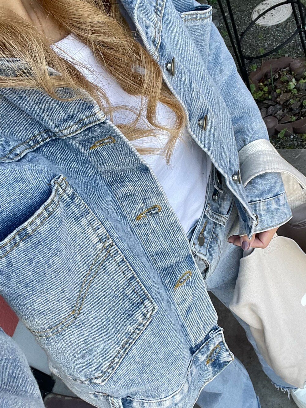 ベージュ系のトートバッグ、ブルー系のデニムパンツ、ブルー系のデニムジャケットを着用したレディースの春コーディネートの3枚目の写真