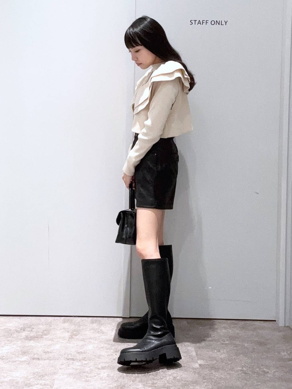 ブラック系のブーツ、ブラック系のボストンバッグ、ベージュ系のニット/セーターを着用したレディースの秋コーディネートの2枚目の写真