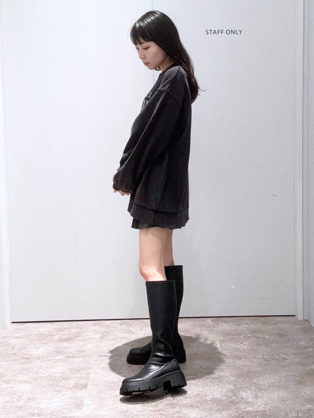 ブラック系のブーツ、グレー系のスカート、グレー系のスウェットを着用したレディースの秋コーディネートの2枚目の写真