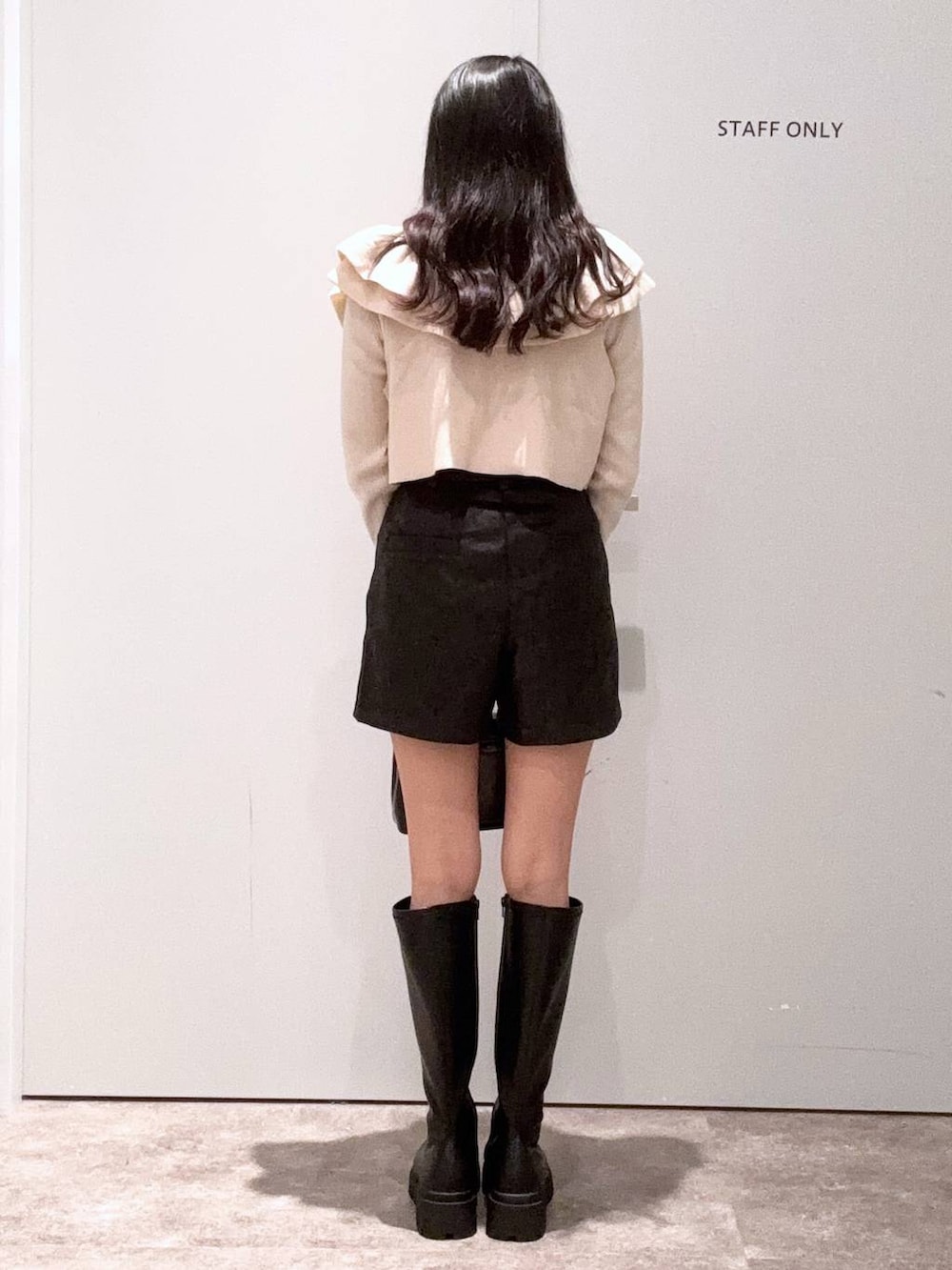 ブラック系のブーツ、ブラック系のボストンバッグ、ベージュ系のニット/セーターを着用したレディースの秋コーディネートの3枚目の写真