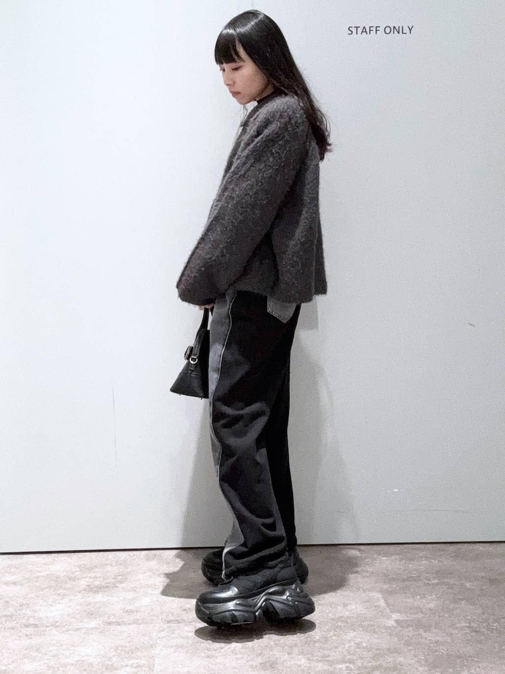 ブラック系のスニーカー、ブラック系のデニムパンツ、ブラック系のボストンバッグを着用したレディースの冬コーディネートの2枚目の写真