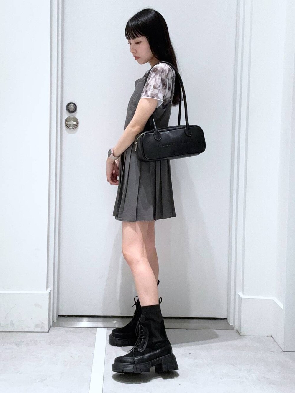 ブラック系のブーツ、ホワイト系のTシャツ/カットソー、ブラック系のボストンバッグを着用したレディースの春コーディネートの2枚目の写真