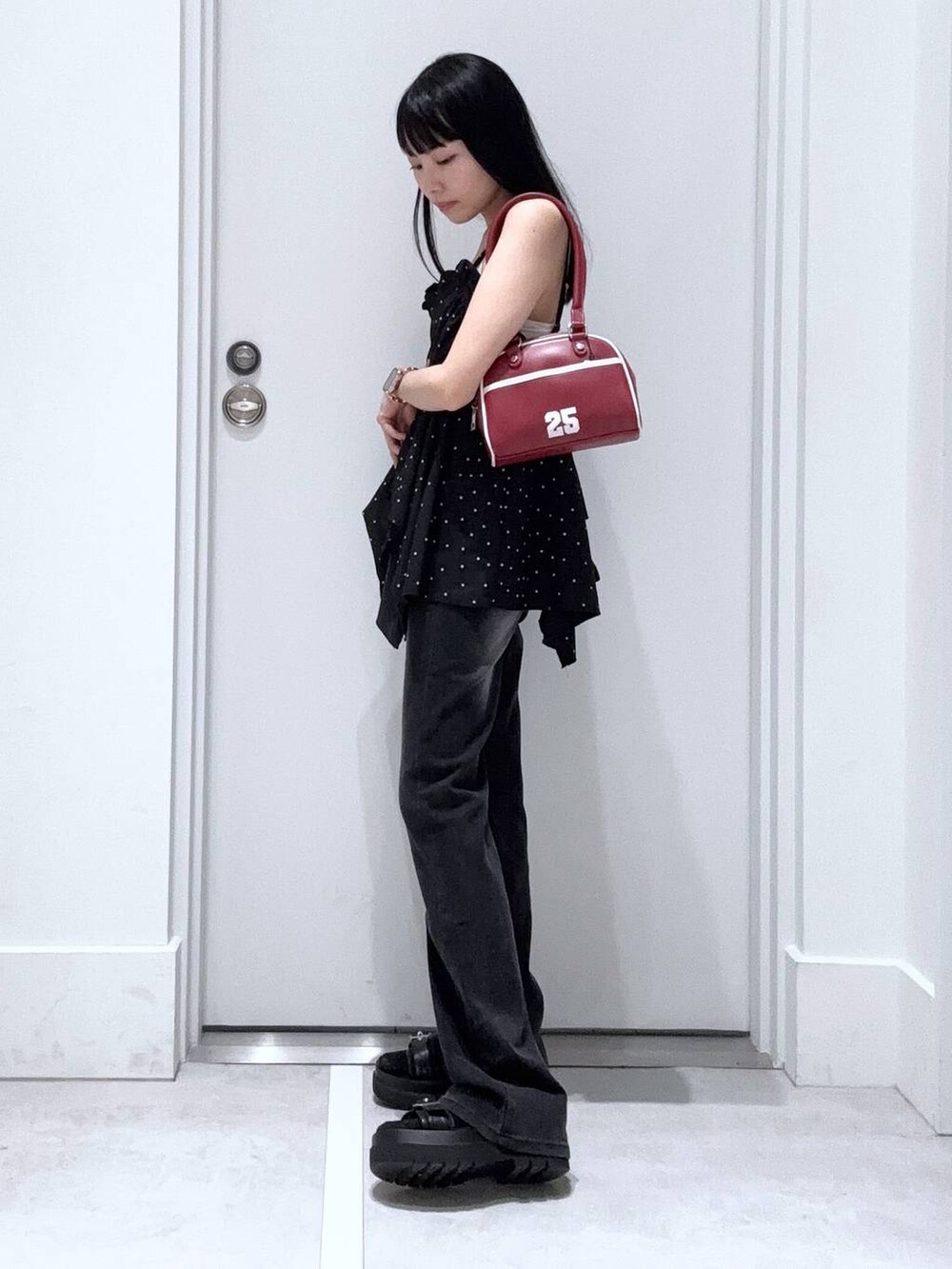 ブラック系のデニムパンツ、レッド系のボストンバッグ、ブラック系のキャミソールを着用したレディースの夏コーディネートの2枚目の写真