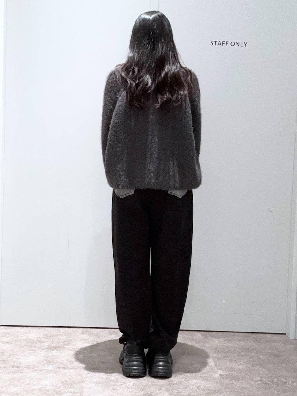 ブラック系のスニーカー、ブラック系のデニムパンツ、ブラック系のボストンバッグを着用したレディースの冬コーディネートの3枚目の写真