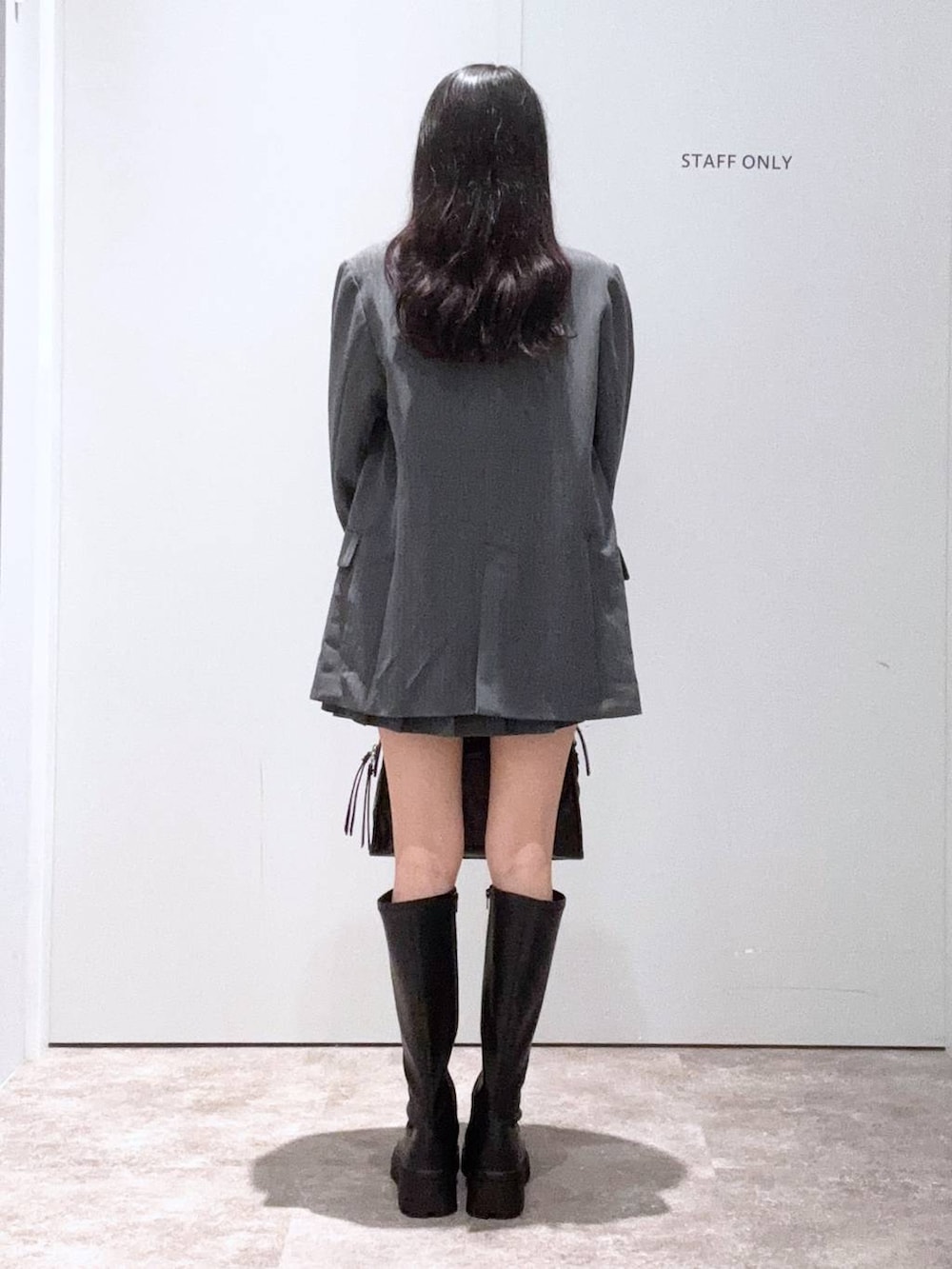 グレー系のテーラードジャケット、ブラック系のボストンバッグ、ブラック系のブーツを着用したレディースの秋コーディネートの3枚目の写真