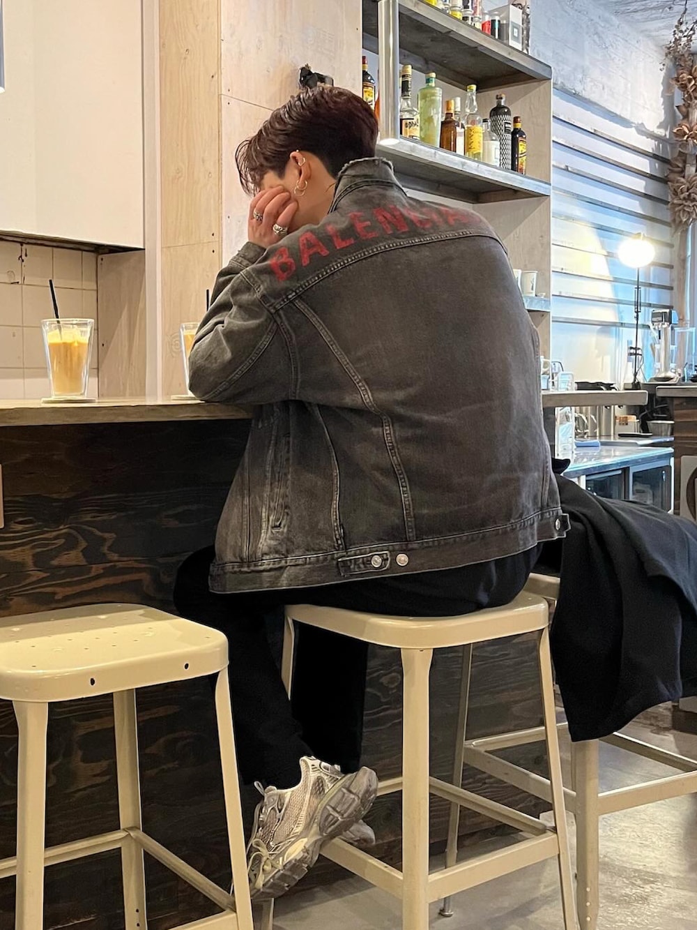 グレー系のスニーカー、ブラック系のデニムジャケット、ブラック系のスラックスを着用したメンズの冬コーディネートの2枚目の写真