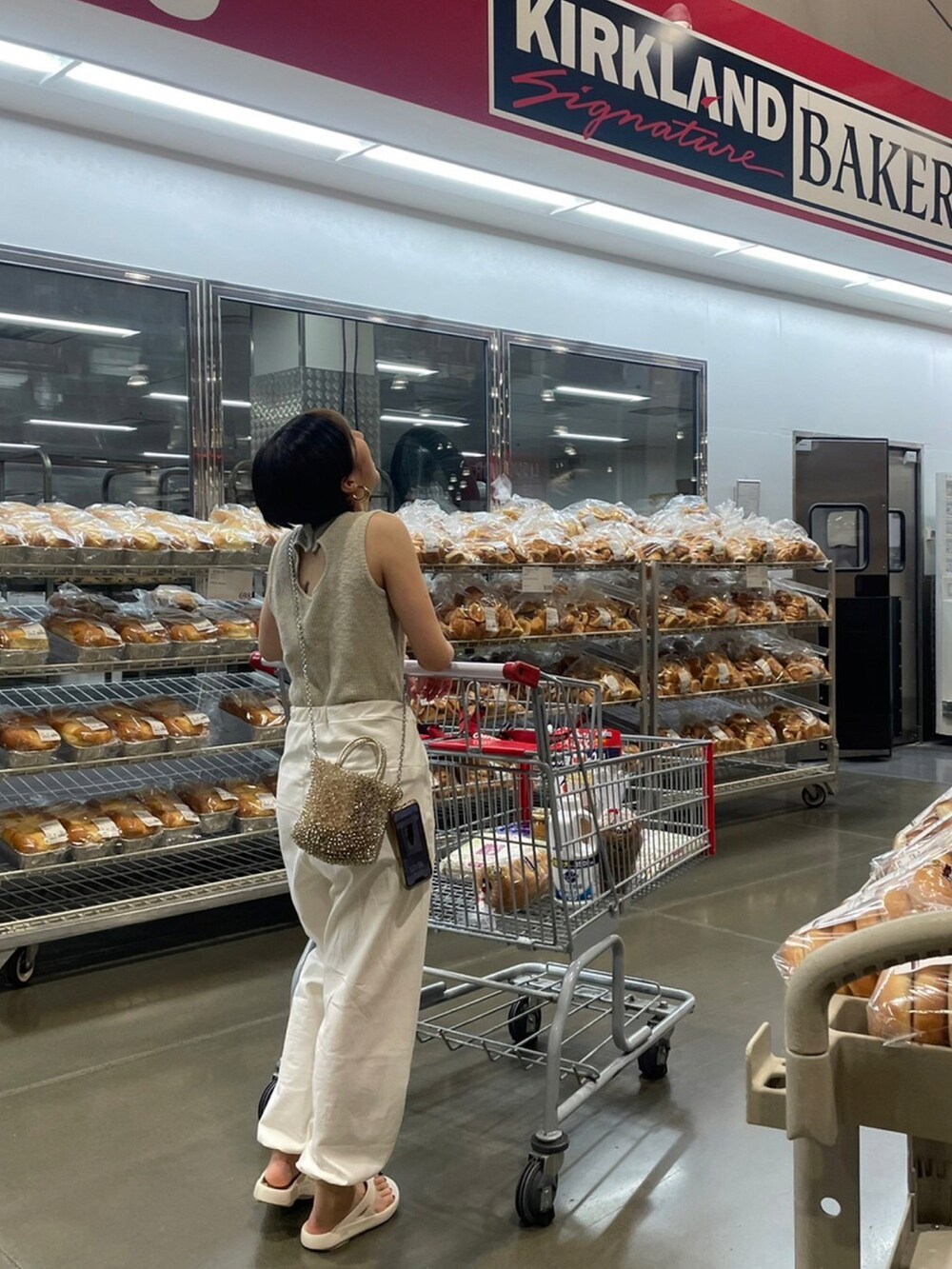 ホワイト系のその他パンツ、ホワイト系のビーチサンダル、ベージュ系のタンクトップを着用したレディースの夏コーディネートの2枚目の写真