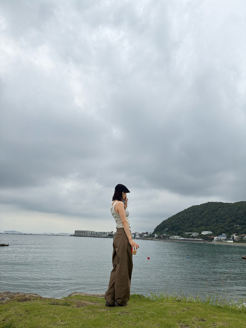 ベージュ系のタンクトップ、ベージュ系のチノパンツ、ブルー系のショルダーバッグを着用したレディースの夏コーディネートの2枚目の写真