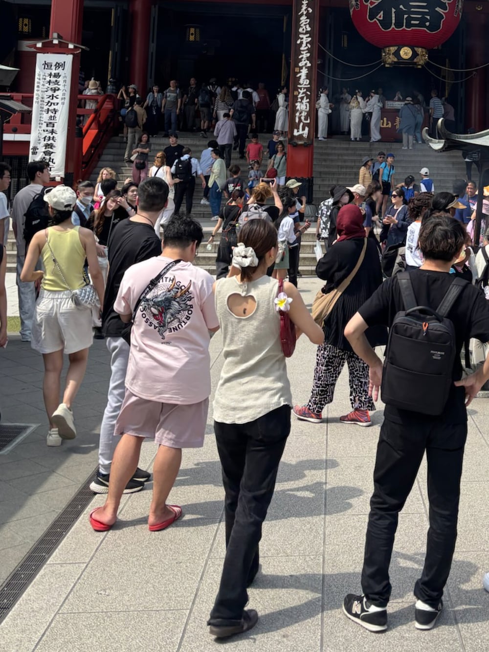 ベージュ系のタンクトップ、ブラック系のデニムパンツ、パープル系のスニーカーを着用したレディースの夏コーディネートの2枚目の写真