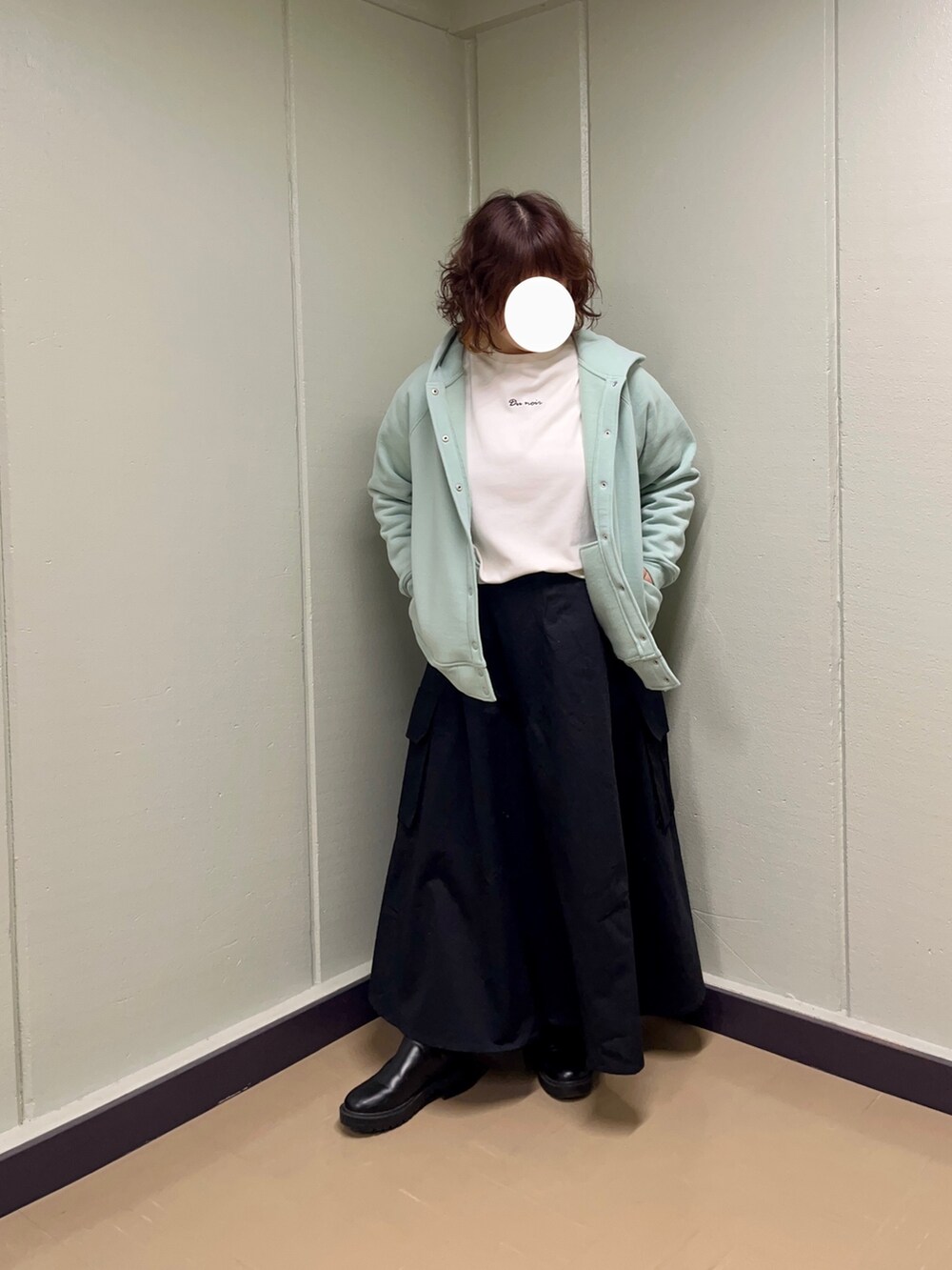 グリーン系のカーディガン/ボレロ、ブラック系のスカート、ホワイト系のTシャツ/カットソーを着用したレディースの冬コーディネートの2枚目の写真