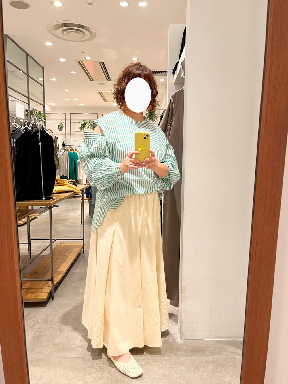 イエロー系のトートバッグ、ベージュ系のスカート、グリーン系のシャツ/ブラウスを着用したレディースの夏コーディネートの2枚目の写真