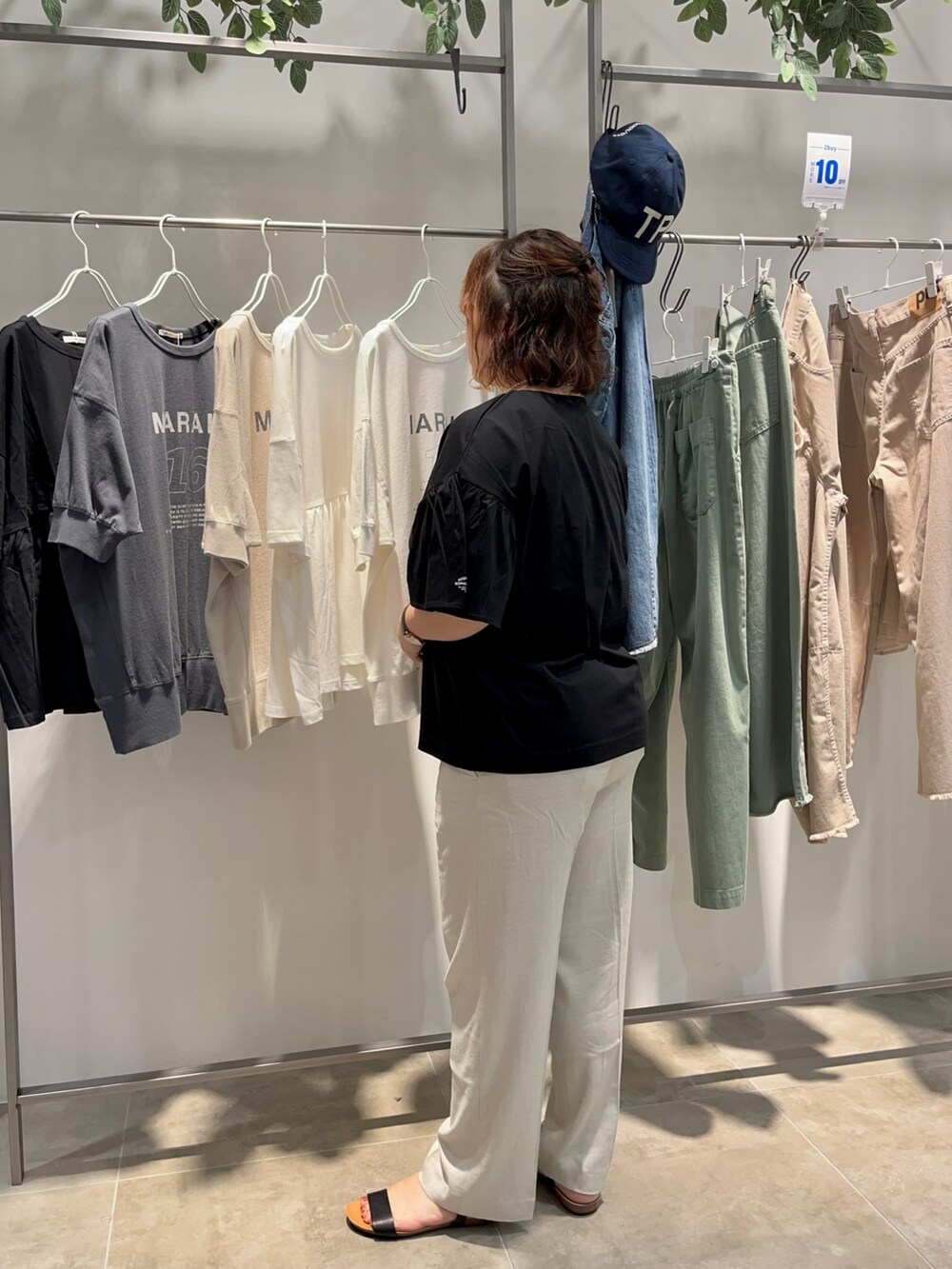 ブラック系のTシャツ/カットソー、ブラック系のショルダーバッグ、ベージュ系のスラックスを着用したレディースの夏コーディネートの4枚目の写真