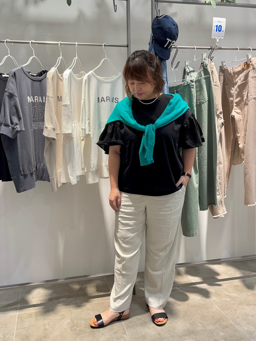 ブラック系のTシャツ/カットソー、ブラック系のショルダーバッグ、ベージュ系のスラックスを着用したレディースの夏コーディネートの2枚目の写真