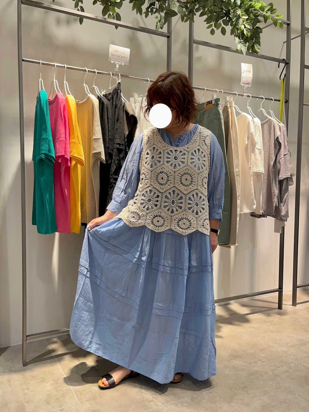 ブルー系のワンピース、ベージュ系のベスト、ブラック系のかごバッグを着用したレディースの春コーディネートの2枚目の写真