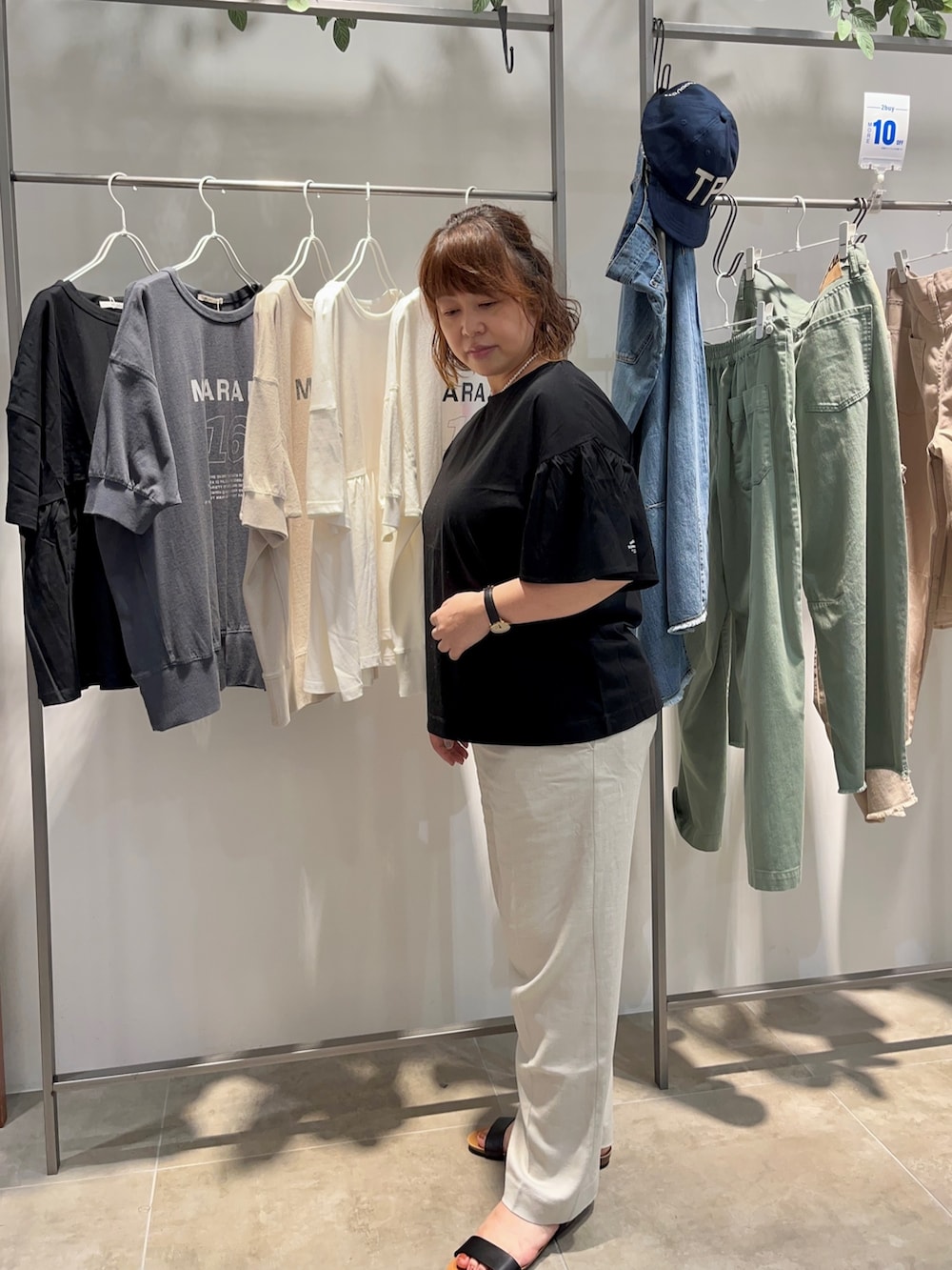 ブラック系のTシャツ/カットソー、ブラック系のショルダーバッグ、ベージュ系のスラックスを着用したレディースの夏コーディネートの3枚目の写真