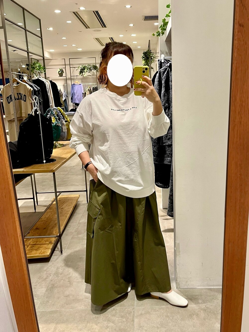 ホワイト系のTシャツ/カットソー、グリーン系のスカート、ベージュ系のトートバッグを着用したレディースの秋コーディネートの2枚目の写真