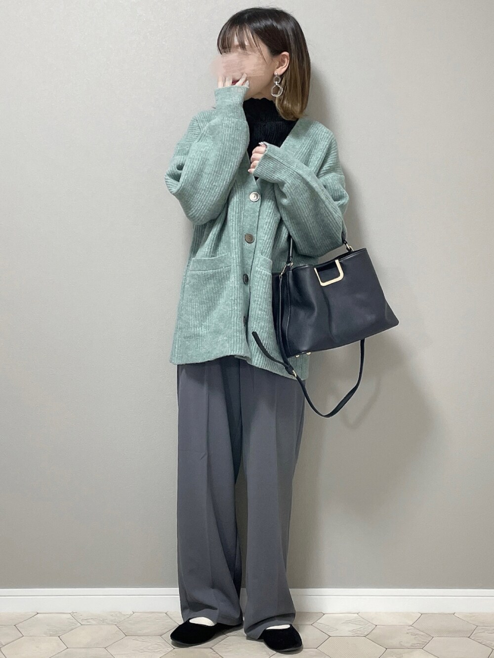 グレー系のスラックス、グリーン系のカーディガン/ボレロ、ブラック系のバレエシューズを着用したレディースの秋コーディネートの2枚目の写真