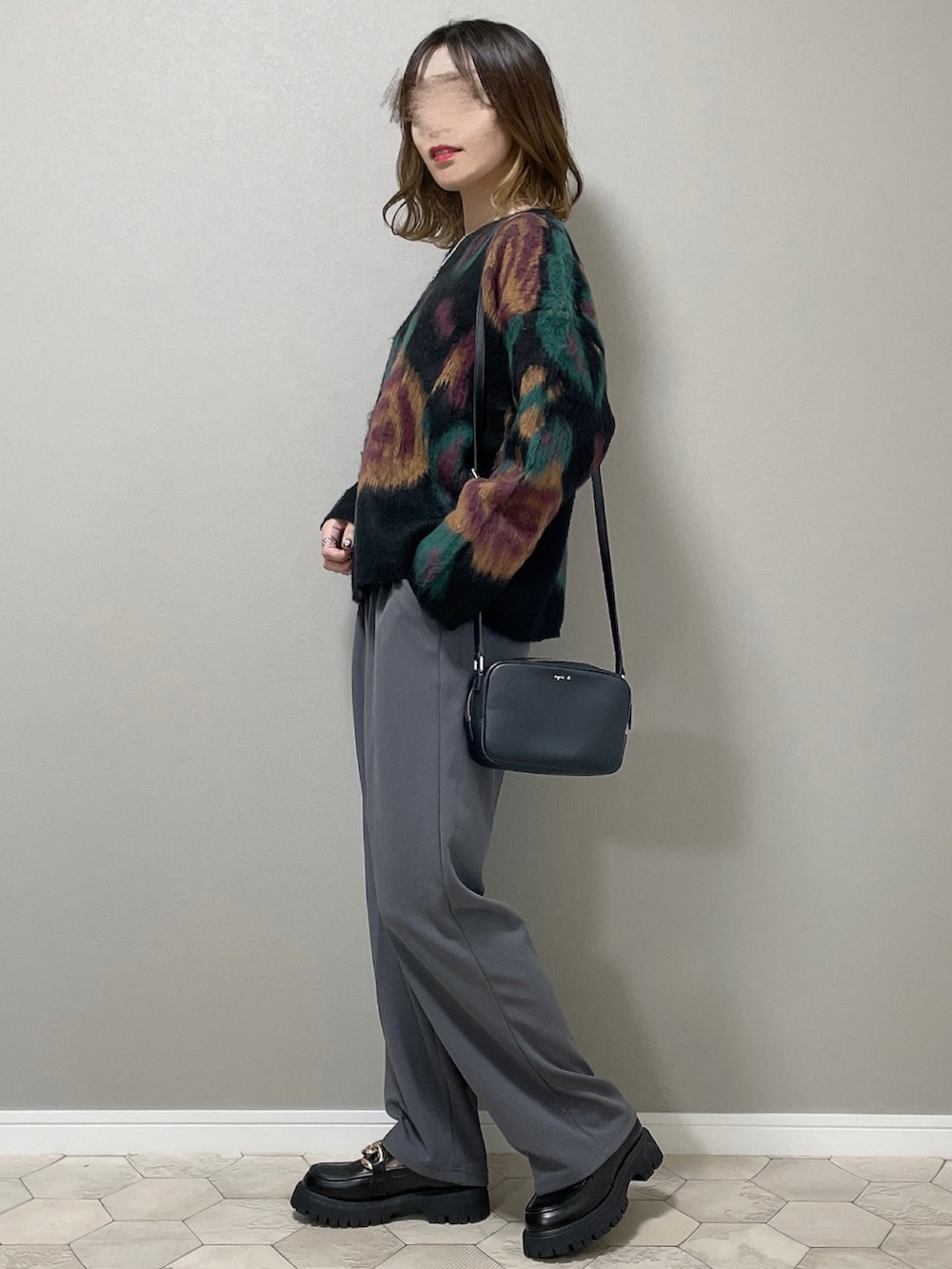 グレー系のスラックス、ブラック系のローファー、ブラック系のニット/セーターを着用したレディースの秋コーディネートの2枚目の写真