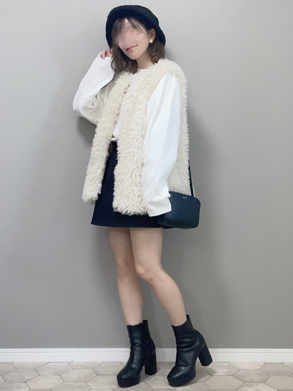 ホワイト系のベスト、ブラック系のブーツ、ブラック系のショルダーバッグを着用したレディースの夏コーディネートの2枚目の写真